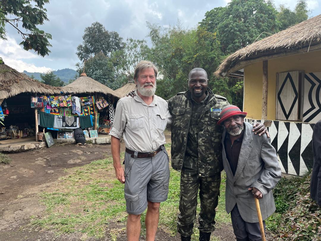 A group of men standing in front of a hut

Description automatically generated